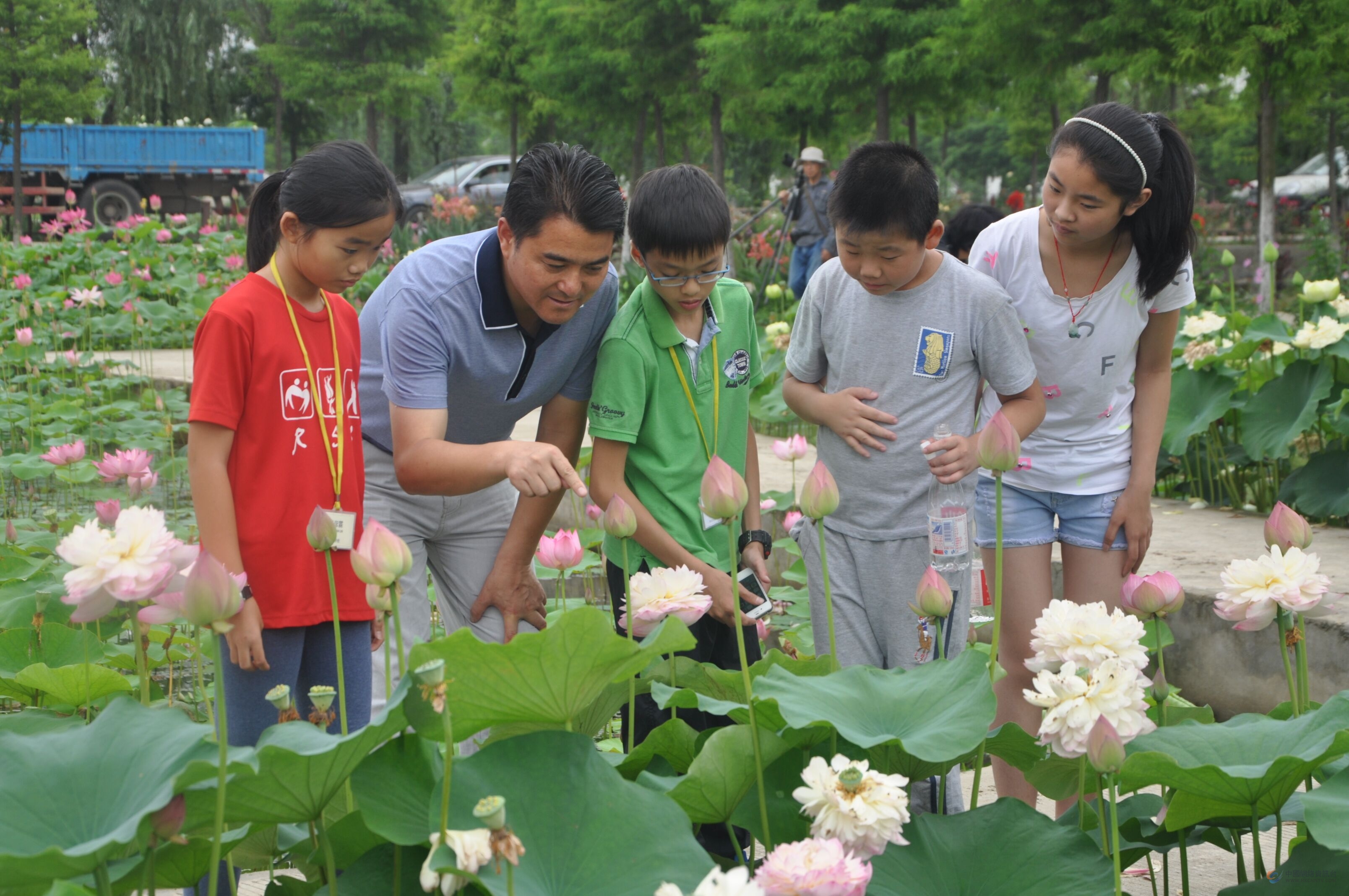 杨瑞清带领孩子在行知小学劳动实践区观察荷花。行知基地供图