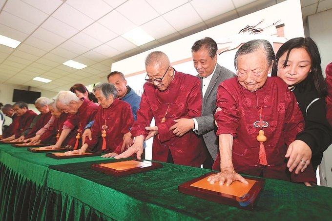 10月4日，9位幸存者老人在手印盒中按下手印。 记者 万程鹏 摄