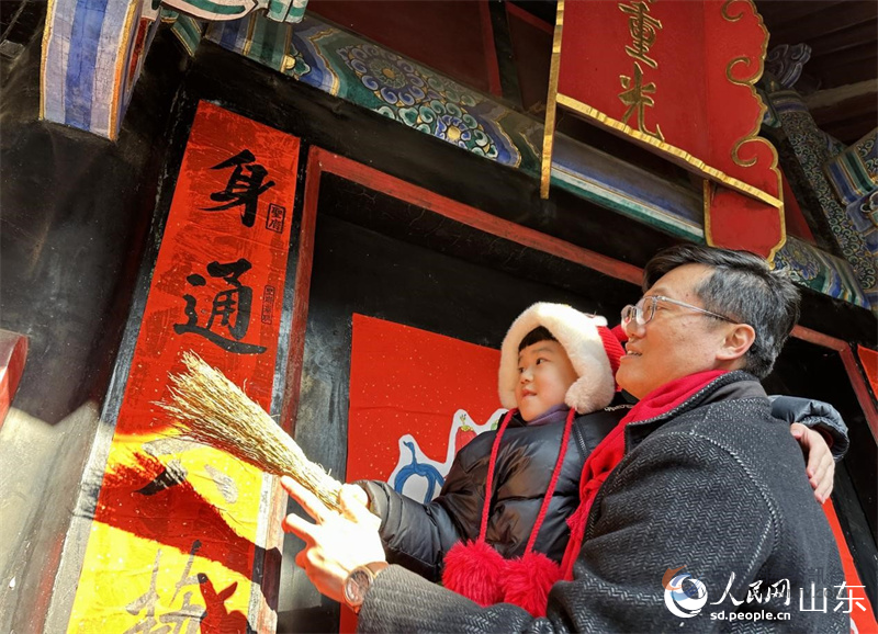 春节前，孔子后裔在孔府重光门前贴春联。 人民网 乔姝摄